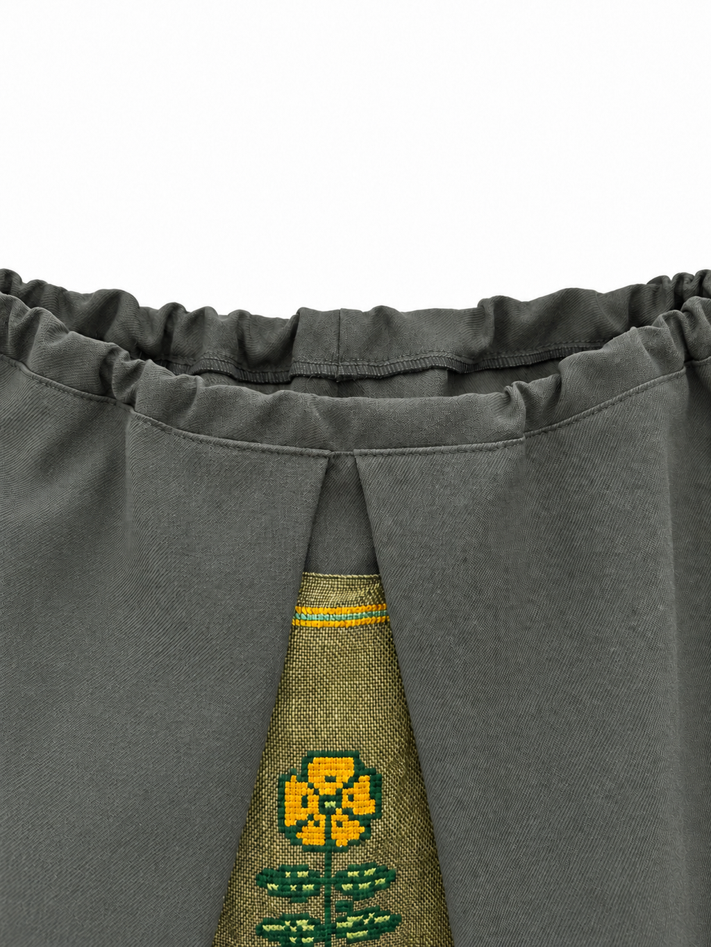 Gathered grey-green wool waistband and yellow floral embroidery detail