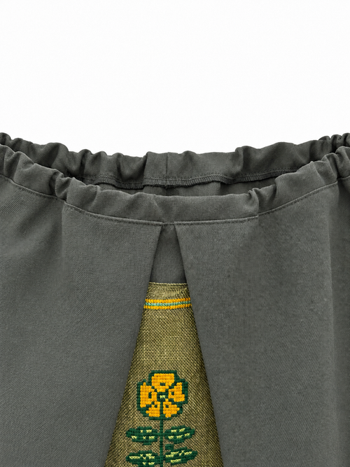 Gathered grey-green wool waistband and yellow floral embroidery detail
