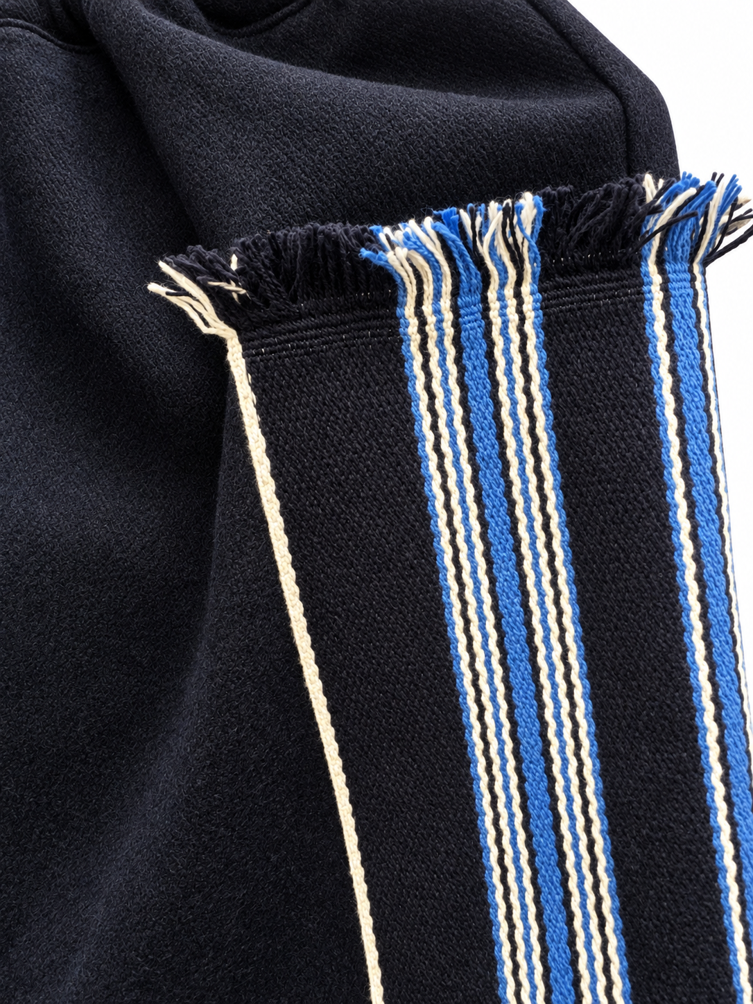 Blue-and-cream striped woven panel with fringed edge on dark wool