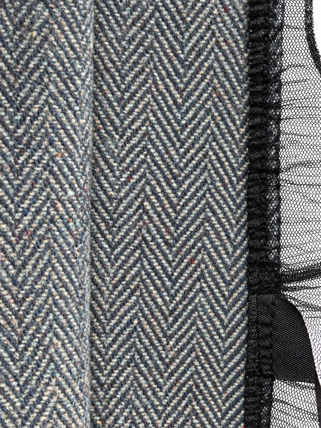 Closeup of grey-blue herringbone fabric and black mesh trim