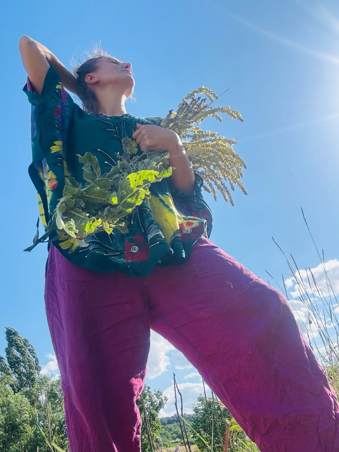 Natalia outdoors holding flowering stems beneath a blue sky