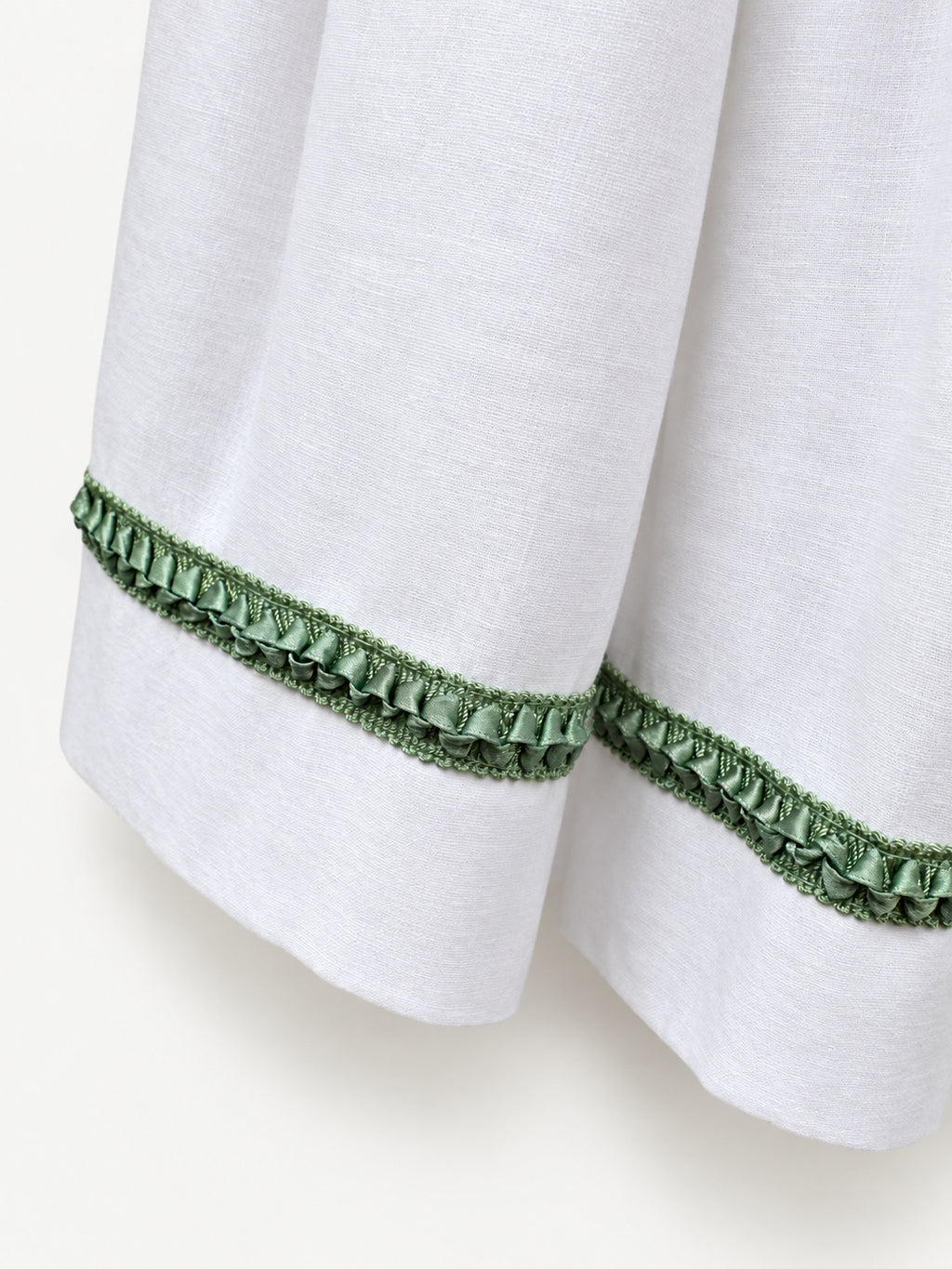 White gathered skirt with green decorative trim near the hem