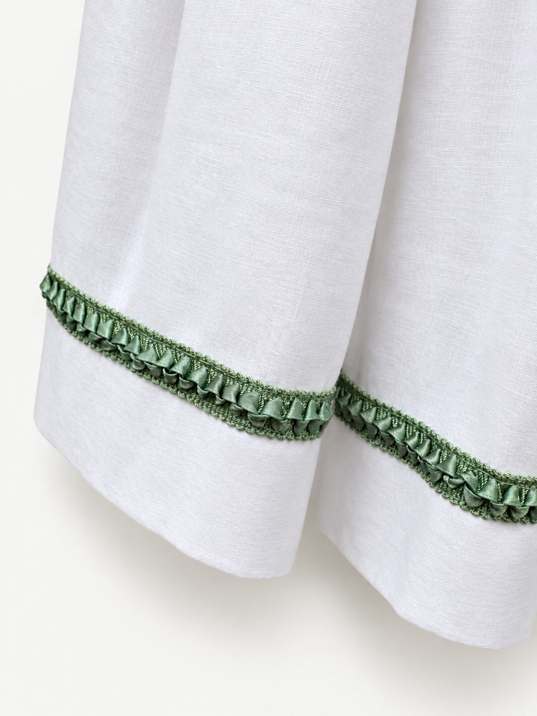 White gathered skirt with green decorative trim near the hem