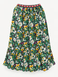 Long floral skirt with white and yellow flowers, a gathered lower tier and red-green zigzag elastic waistband