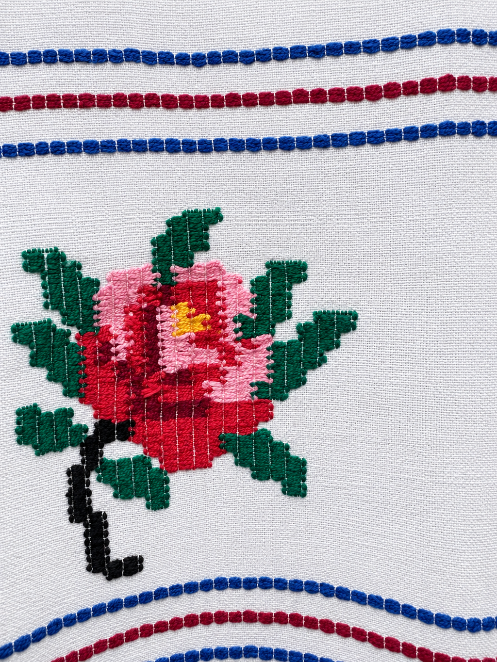 Pink and red rose embroidery with green leaves and blue and burgundy stitched stripes